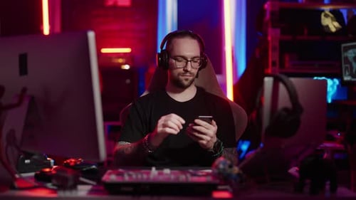 Man Using Computer and Phone in Neon Room
