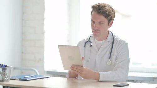 Young Doctor Browsing Internet on Tablet in Clinic