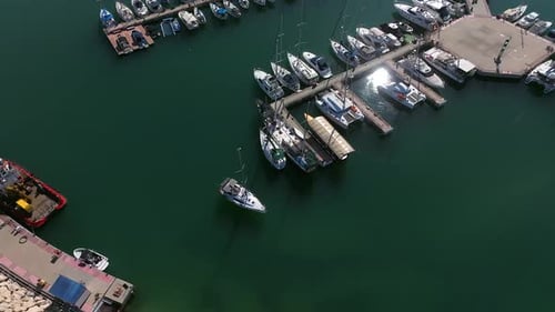 Aerial view of a Small sail boat leaving a marina slowly
