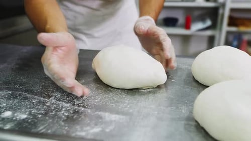 Chefkoch formt in einer Bäckereiwerkstatt Brotlaib aus Hefeteig