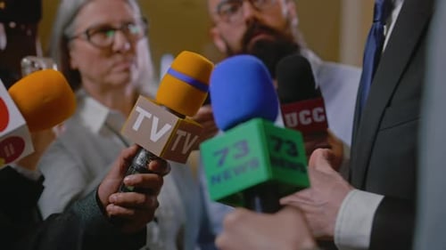 Reporters Holding Microphones at Press Conference