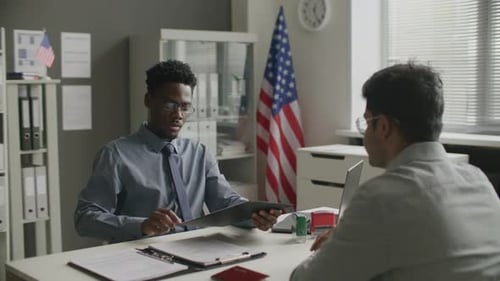 Black Consular Officer Conducting Visa Interview with Applicant at US Embassy