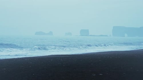 The rocky coastline of Iceland over night with waves crashing on the black sand beach