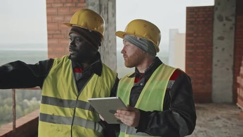 Construction Workers Examining Tablet in Unfinished Building