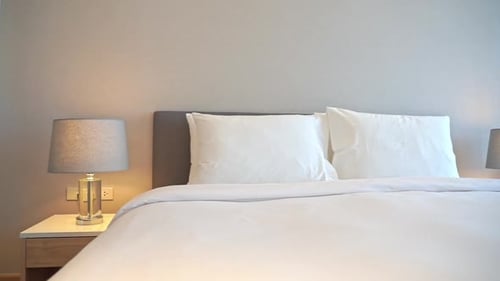 Clean crisp white bed linen and golden lamps on bedside tables glowing in upscale luxury resort bedr