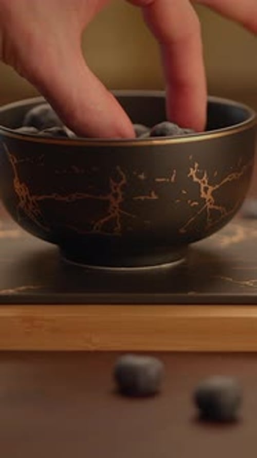 Hand Puts Blueberry from Bowl