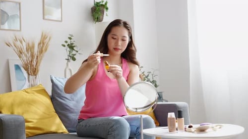 Woman Applies Facial Serum in Bright Home Interior