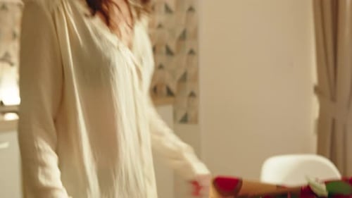 Woman Smiling over Roses in Kitchen