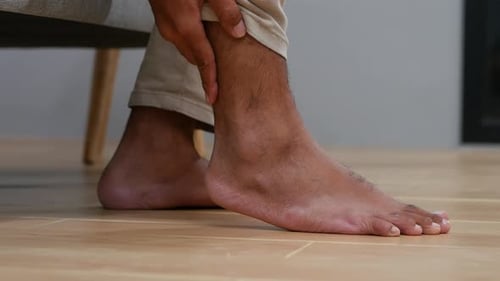 Close up Unrecognized Man's hand holding ankle, suffering from pain in ankle and foot