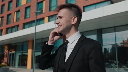 Young Man Celebrating Success on Phone Outside Office