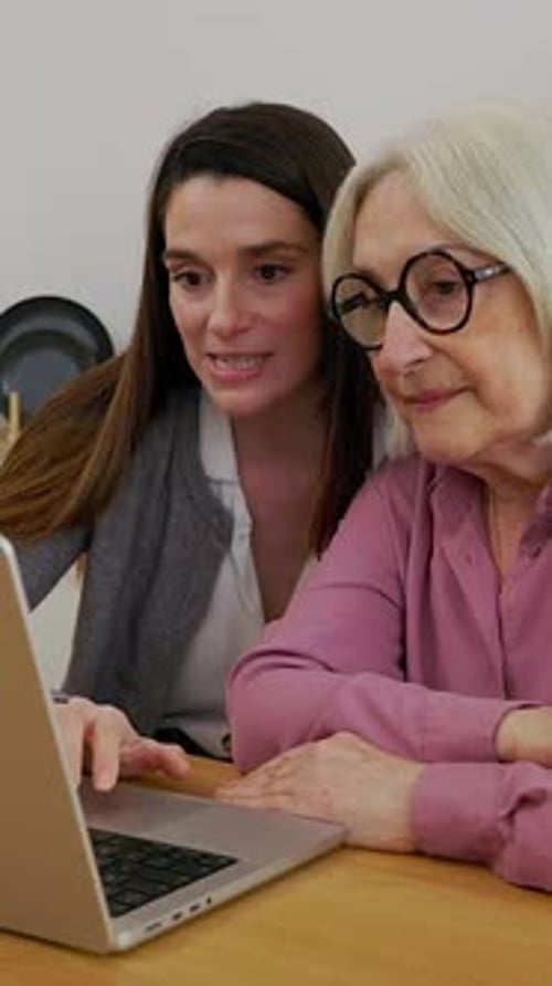 Young Woman Helping Senior Woman Use Laptop