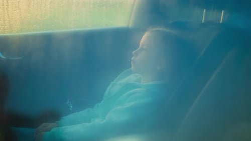 Pensive Child Waits for Parents in Car on Rainy Day