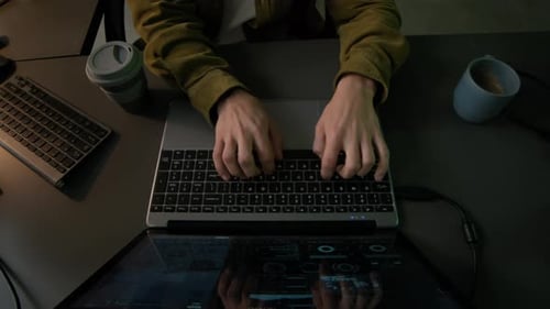 Young Male Programmer Typing on Laptop in Office in Evening