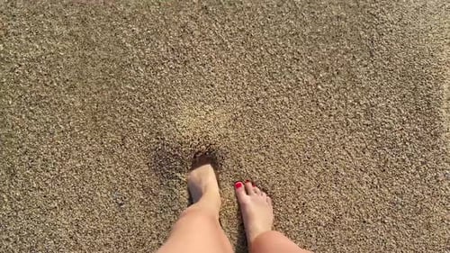 Female legs feet and waves of sea water salty on the beach with yellow sand on the sea with splashes