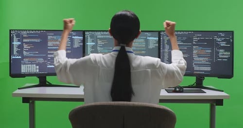 Happy Asian Woman Developer Celebrating While Write Code With Multiple Screens In Green Screen