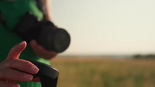 Female Photographer Adjusting Camera Strap in Sunset Field
