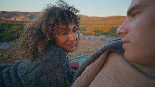 Affectionate Couple Bundled in Blankets at Sunset