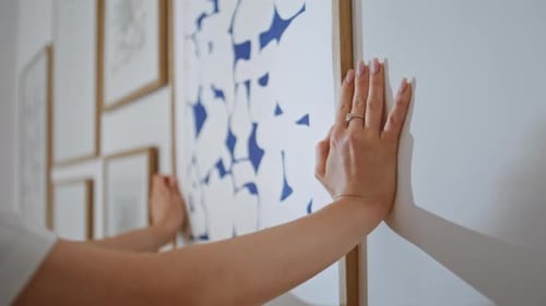 Woman Adjusting Modern Art Print on Wall