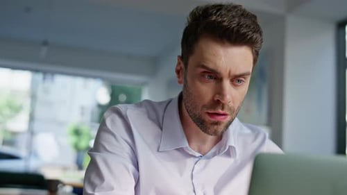 Man Looks Intently at Laptop in Office
