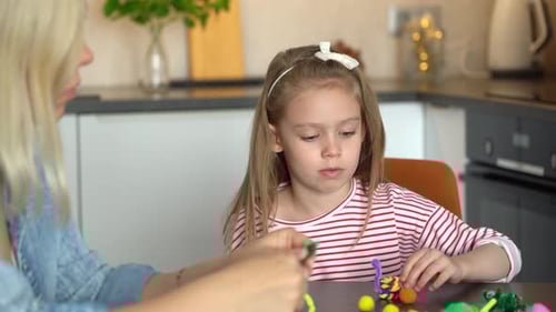 Child and Woman Crafting Colorful Clay Figures at Home