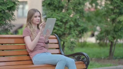 Young Woman Uses Tablet Device in Park