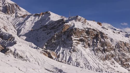 Aerial shot of rugged snow-covered mountain slopes illuminated by golden sunlight