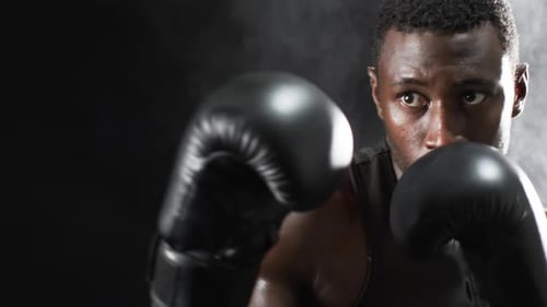 African American boxer training intensely in the gym on a black background