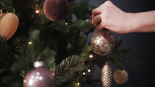 Hands Decorating Christmas Tree with Festive Ornaments