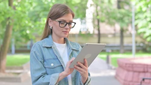 Young Woman Using a Tablet in a Park
