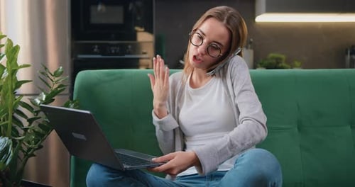 Woman Talking on Phone While Using Laptop