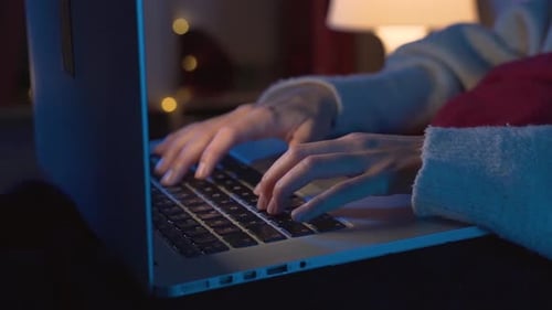 Hands of Young Woman Working with Her Laptop in the Bed in the Middle of the Night