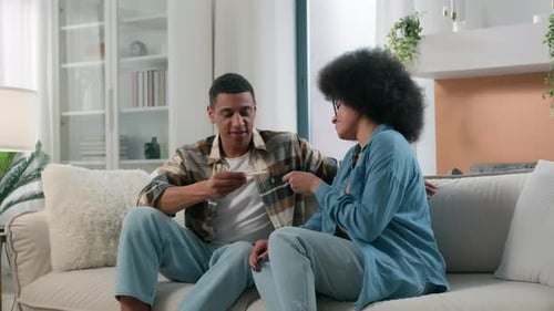 Young Couple Looking at Pregnancy Test on Couch