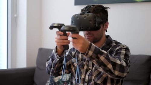 Young Man Using Virtual Reality Headset and Controllers
