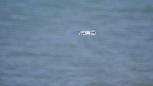 Drone DJI Mini 2 flying hovering over sea water, hovering with wind, flying drone