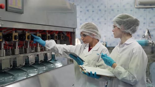 Une travailleuse inspecte la qualité de l'eau et des bouteilles dans une usine de production d'eau potable