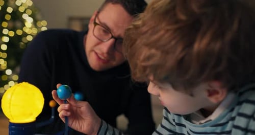Father and Son Study Solar System Toy at Home
