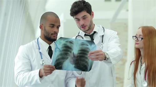 Three Confident Doctor Examining Xray Snapshot of Lungs in Hospital
