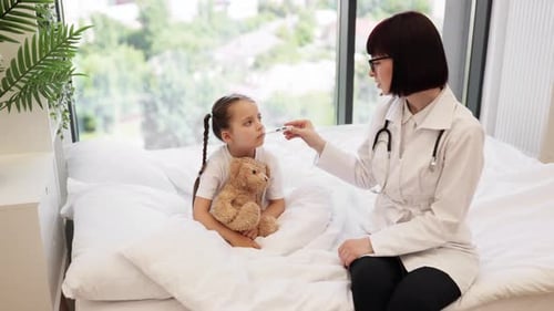 Doctor Checking Thermometer Readings of Small Child in Bed