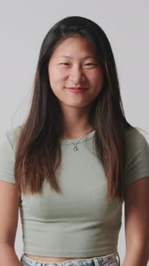 Young woman looking at camera smiling and laughing isolated over white background in studio