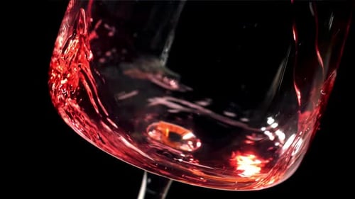 Rotwein, der in ein Glas auf schwarzem Hintergrund fließt, gefilmt mit einer Hochgeschwindigkeitskamera mit 1000 Bildern pro Sekunde