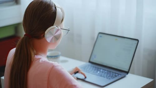 Teenage Girl Using Laptop With Headphones Indoors