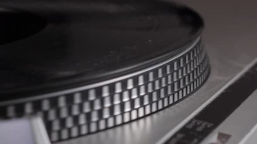 Slow motion edge shot of black vinyl record spinning on antique turntable that comes to a stop. Old