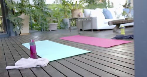 Water bottle, towel and exercise mats on sunny terrace