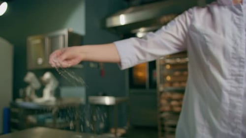 professional chef throws flour on table stirs it before preparing bread pastry in bakery