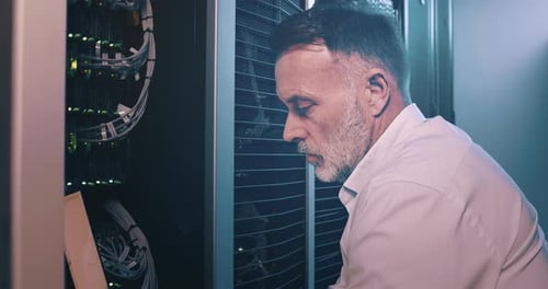 Man Working in Server Room with Laptop