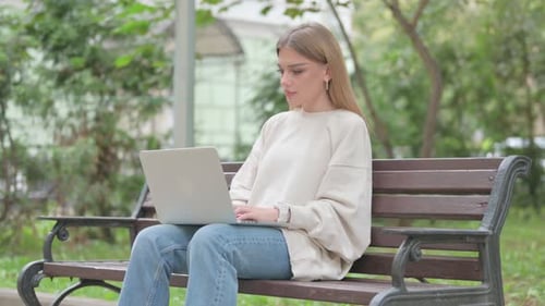 Woman Using Laptop on Park Bench