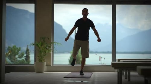 A Man Exercises in a Scenic Indoor Setting with Stunning Mountains and a Beautiful Lake View