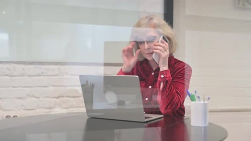 Mature Woman on Phone at Desk with Laptop
