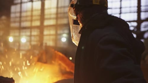 Worker in Protective Gear Observing Molten Metal Pour