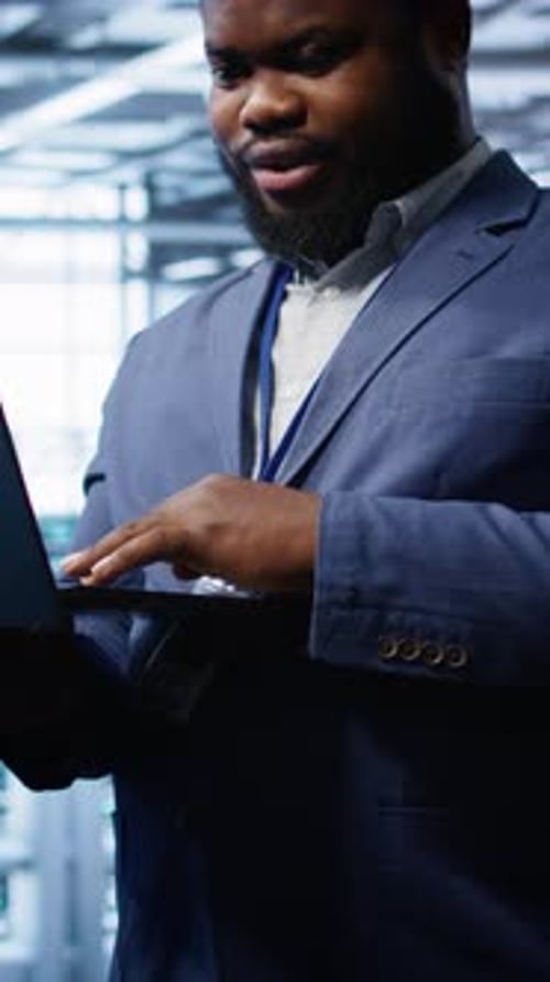 Vertical Video Computer Scientist in Server Hub Checking Recovery Plan on Laptop